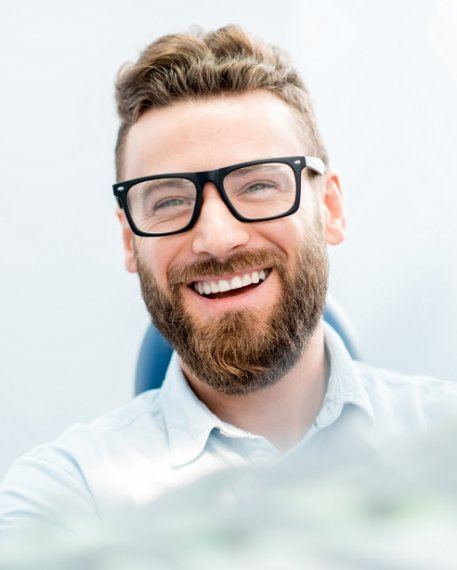 Man with beard and glasses grinning in dental office