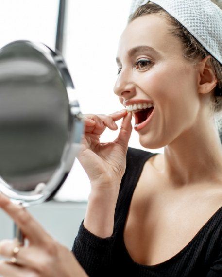 Woman placing at home teeth whitening tray in her mouth
