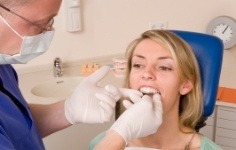 Blonde woman in dental chair receiving dental exam