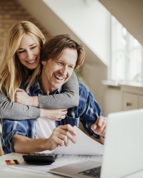 Smiling man and woman looking at laptop