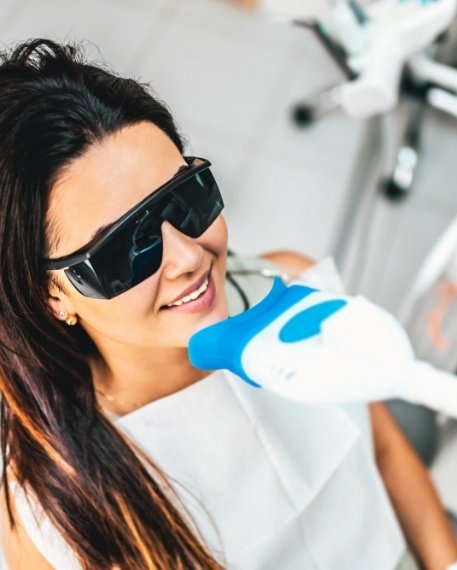 Woman getting her teeth whitened in dental office