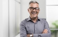 Older man smiling with arms crossed