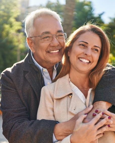 Smiling man and woman hugging outdoors