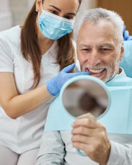 Dentist showing smiling patient reflection in mirror