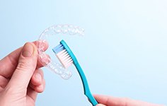 Patient holding an Invisalign tray and a toothbrush