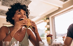 Woman grinning as she’s about to bite into a sandwich 