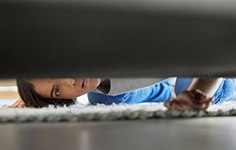 Woman looking under the couch for her Invisalign tray