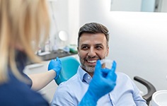 Dentist holding a patient’s Invisalign tray while he smiles