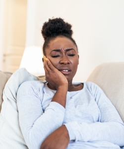 Woman on couch experiencing toothache