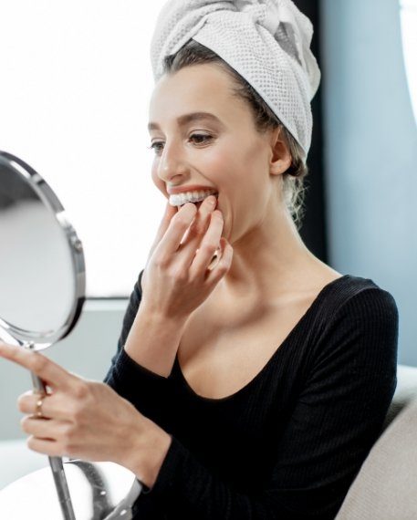 Woman putting at home teeth whitening tray in her mouth