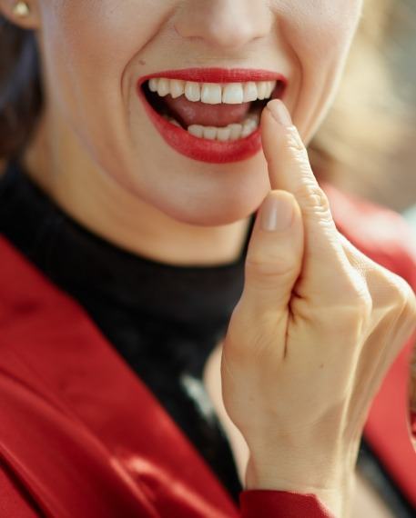 Woman with red lipstick looking at her teeth in mirror