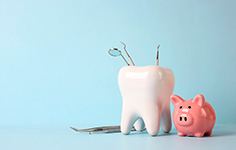 Large model tooth next to pink piggy bank with light blue background